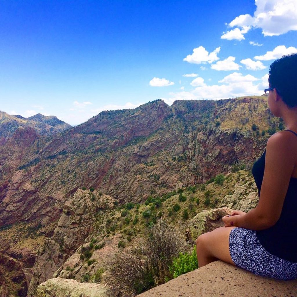 black backpacker sitting on a cliff